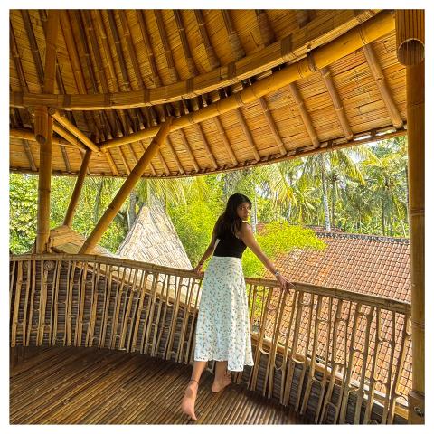 A person stands on a balcony inside a building made from bamboo.