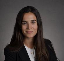 Antonia Vazquez Antonia Vazquez stands in front of a grey background wearing a black blazer and a white shirt, with a gold necklace.