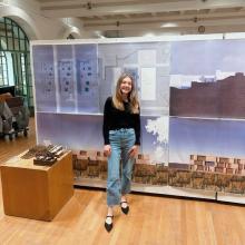 Emma Martin A woman in a black shirt and jeans stands in front of a display at a gallery.