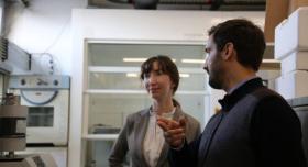 Two people talk to each other in a laboratory.