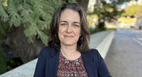A woman wears businesswear and stands outdoors.