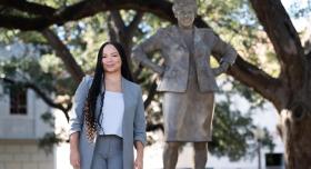 A person wears a suit and stands next to the Barbara Jordan statue.