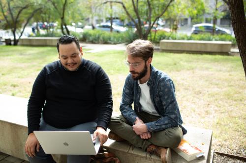 two students outside looking at computer