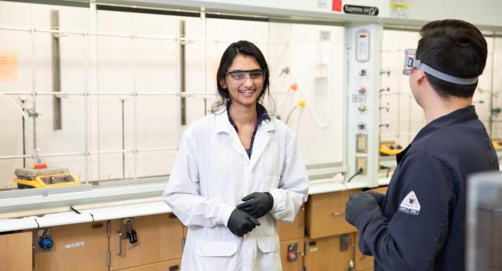 Graduate researcher talks to colleague in lab